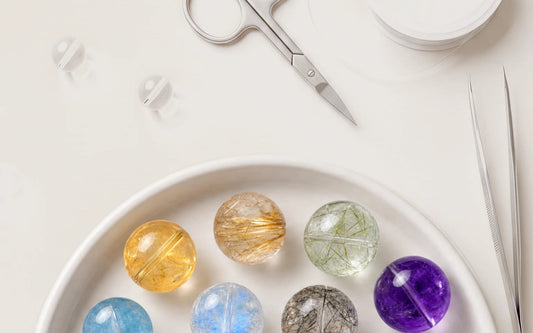 Colorful natural crystal beads arranged in a design tray beside bracelet-making tools