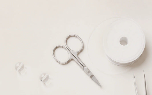 Bracelet cord, scissors, and crystal beads arranged on a clean ivory worktable