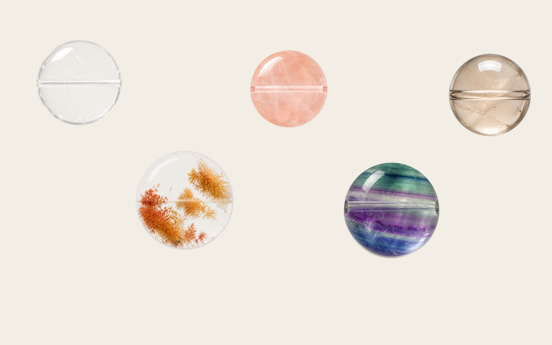 Several natural crystal beads showing distinct colors, clouds, bands, and mineral inclusions